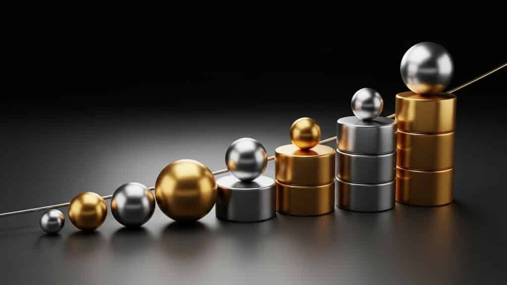 Gold and silver spheres are stacked on matching gold and silver cylinders, arranged in a progressive staircase