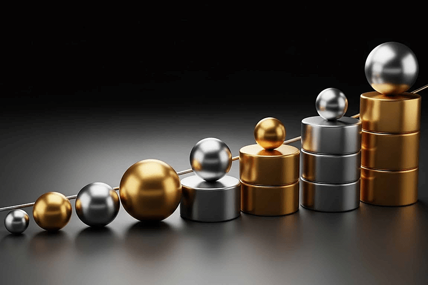 Gold and silver spheres are stacked on matching gold and silver cylinders, arranged in a progressive staircase