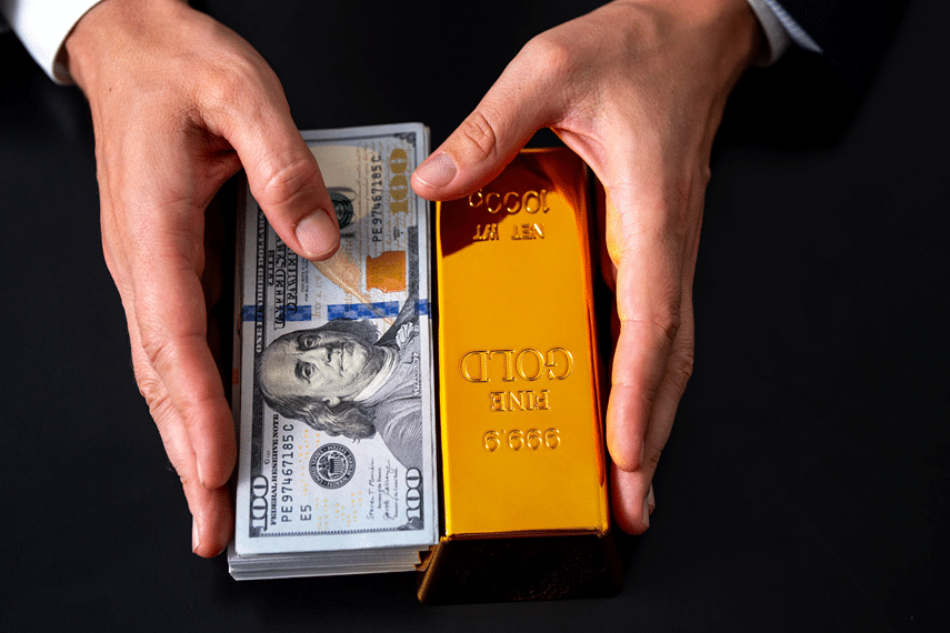 Hand holding gold bars and dollar bills