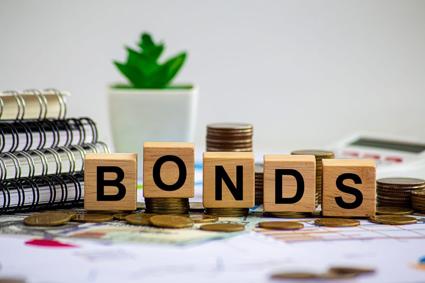 Bonds spelled out in tiles on table with plant and coins